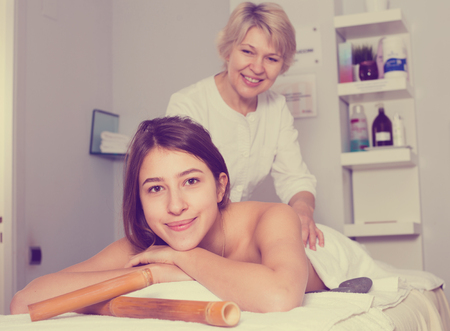 Young smiling woman having professional massage in spa salonの写真素材