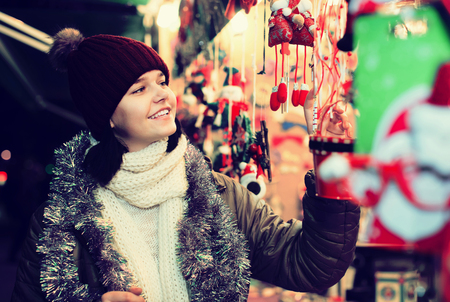 smiling american girl choosing Christmas decoration at marketの写真素材