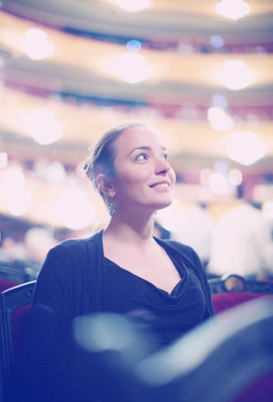 Portrait of positive young woman in auditorium of opera teatre