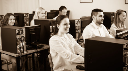 Working team sitting at desks in office and looking at PC screens. Focus on woman