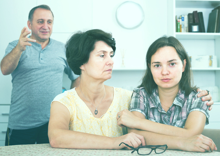 Senior woman sitting with young unhappy woman and trying to help indoorsの写真素材