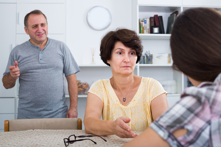 Worried mature woman listening to daughter and trying to help at homeの写真素材