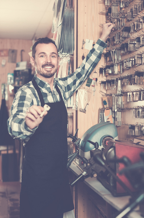 Smiling european male worker showing key he made in repair workshopの写真素材