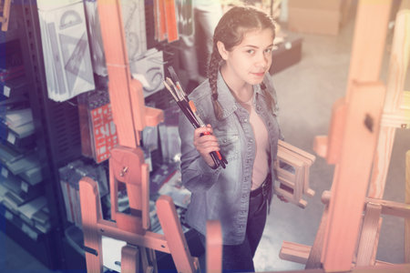 Smiling teenage girl shopping various supplies in art supply shopの写真素材