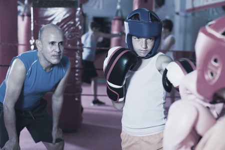 Group of kids practicing with instructor on boxing ring at gymの写真素材