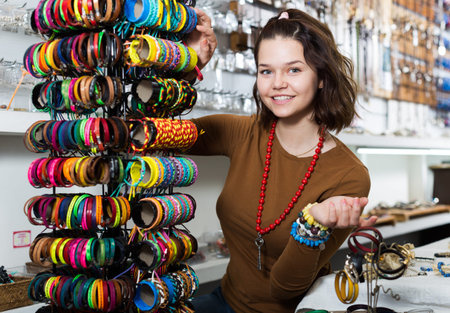Young girl seller offering colored bracelets on the stand