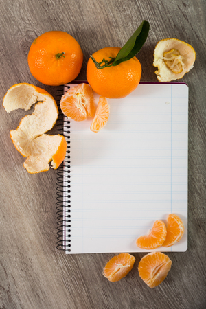 Notebook in range surrounded by fruitの写真素材