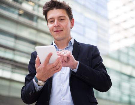 Professional man in jacket working at electonic device outdoorの写真素材