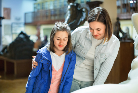 Smiling mother and daughter regarding ancient statues in museumの写真素材