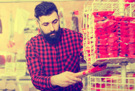 Smiling guy deciding on best pasta in butchers shopの写真素材