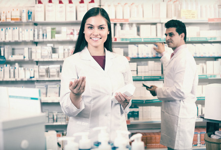 Two positive smiling professional pharmacists in uniform at the work in modern pharmacyの写真素材
