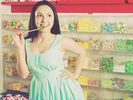 Pretty girl sucking   lollipop in the sweets storeの写真素材