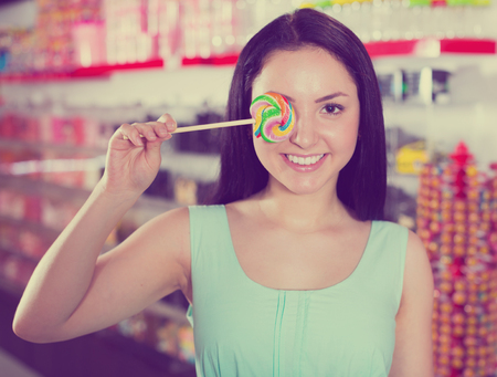 Portrait of  girl  with lollypop at candies shopの写真素材