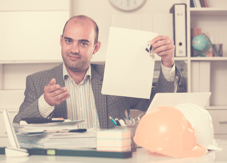 Employee of construction company sitting near helmet at the tableの写真素材