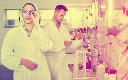 Two efficient smiling positive researchers in white coat checking wine acidity and sugar saturation in chemical laboratoryの写真素材