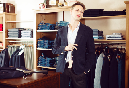 Shopper is trying on new dark blue jacket in male clothes store.の写真素材