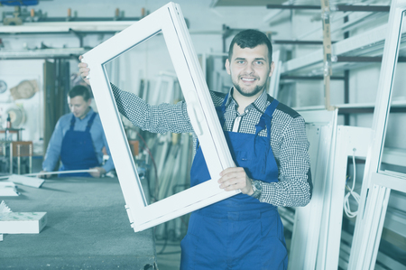 Smiling careful adult workman showing PVC manufacturing output in workshopの写真素材