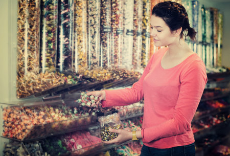 Young cheerful woman with candies at sweets shopの写真素材