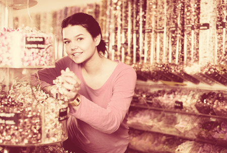 Happy brunette girl buying candies at shopの写真素材