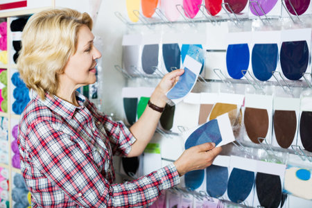 Positive customer woman picking textile patch in sewing shop