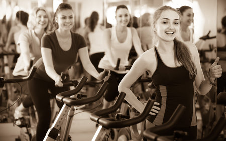 Positive  smiling blonde girl and other females working out in sport club