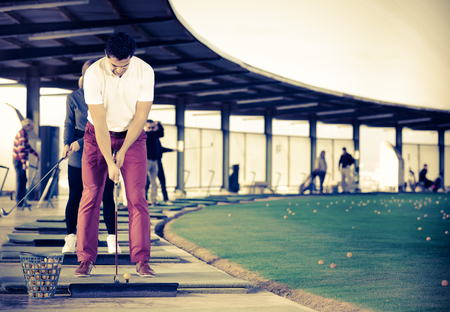 smiling man playing golf is going to hit ball at golf courseの写真素材
