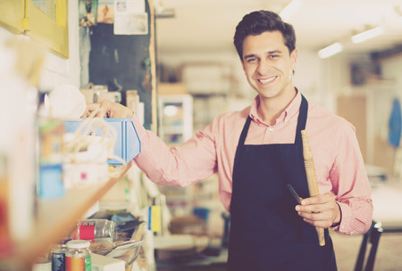 Portrait of craftsman with tool in hand near shelves in carpentryの写真素材