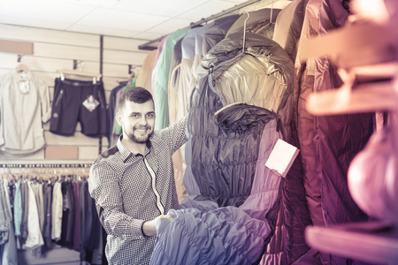 Young guy choosing new sleeping bag in sports equipment storeの写真素材