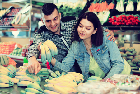 Smiling couple examining various fruits in grocery shopの写真素材