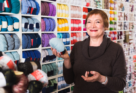 Woman is buying colorful yarn for their hobby in needlework shop.の写真素材