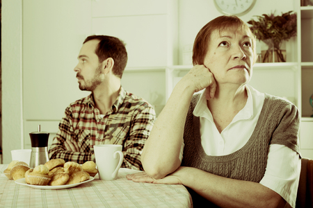 Aged mother arguing with her adult son at homeの写真素材