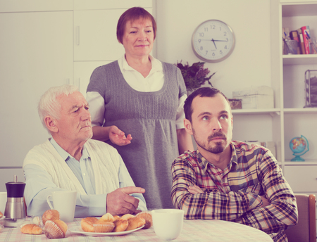 Elderly grandfather teaches his grandson in presence of grandmotherの写真素材