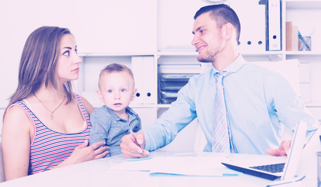 mother and little boy andadvising with adult banker worker in modern officeの写真素材
