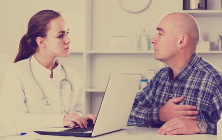 Man client visiting consultation with female doctor in hospitalの写真素材