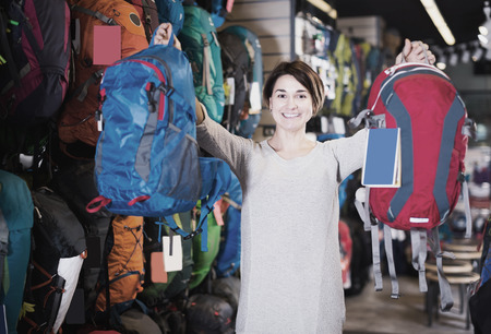 Smiling girl bragging about buying backpacks in a sporting goods storeの写真素材