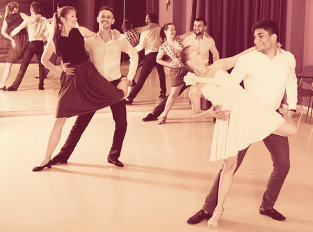 Adult dancing couples enjoying latin dances in modern studioの写真素材