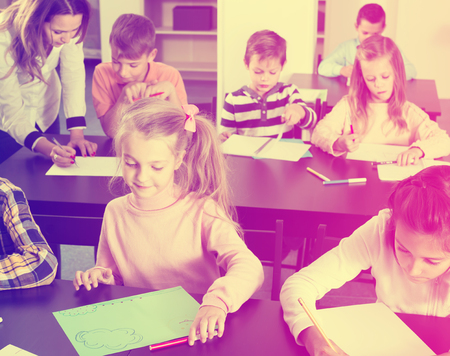 busy little children with teacher drawing in classroom on the lessonの写真素材