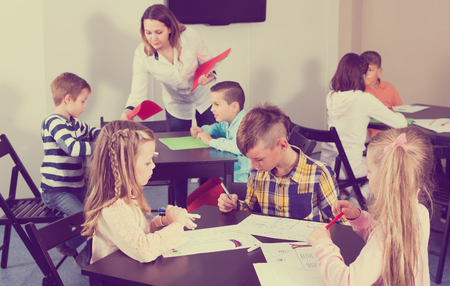 concentrated little children with teacher drawing in classroom on the lessonの写真素材