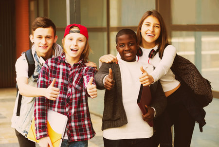 Portrait of four attractive teenage students close to university