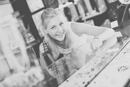 Cheerful young female shopping earrings in jewellery boutiqueの写真素材