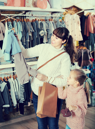Pregnant female and girl child choosing  babys clothes in childrens storeの写真素材