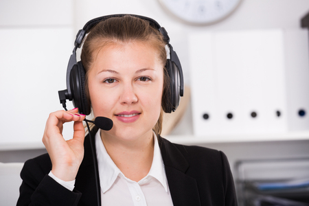Portrait of operator in black suit which is talking by headset with client in the office.の写真素材