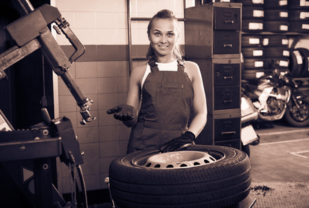 Mechanic woman working on car wheel in service pointの写真素材