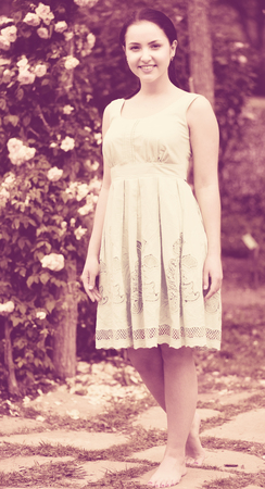 portrait of young happy germany female in  dress  near roses in a parkの写真素材