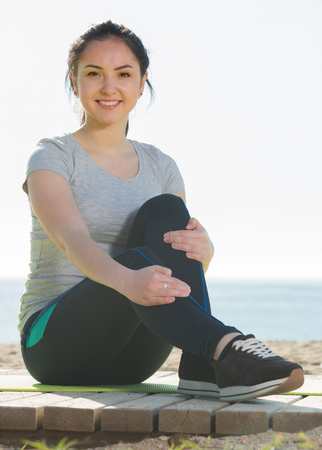 Smiling girl preparing for regular training on beachの写真素材