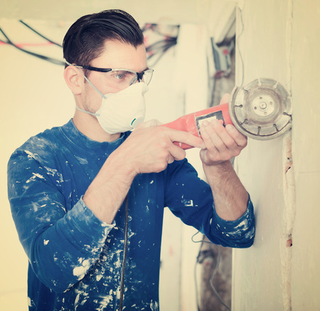Construction male worker cutting concrete wall by using handheld circular sawの写真素材