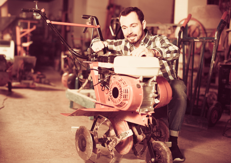 Positive man worker practicing his skills with plough at workshopの写真素材
