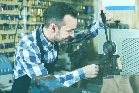 Young male worker making key in specialized workshopの写真素材