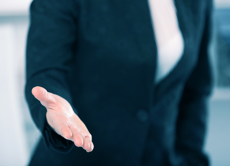 Woman office worker in black suit offering one's handの写真素材