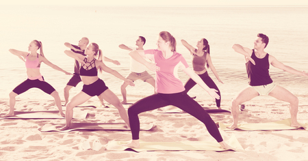 Yoga on beach, group of people practicing healthy lifestyleの写真素材